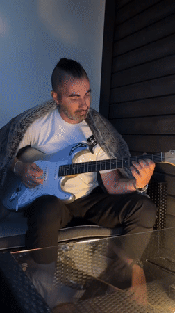 Man with mohawk plays guitar alongside Pomeranian in Oslo home