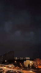 Stormy night cityscape captured with wet streets, illuminated buildings