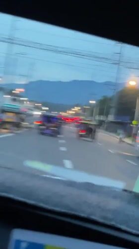 Car travels past tricycles on mountain-view road in Davao