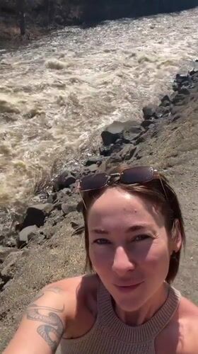 Woman films selfie video by turbulent river in Russia
