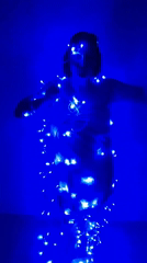 Woman dances with fairy lights in blue-lit room