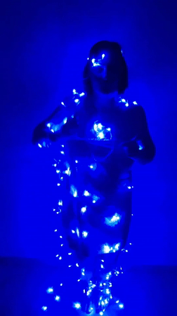 Woman dances with fairy lights in blue-lit room