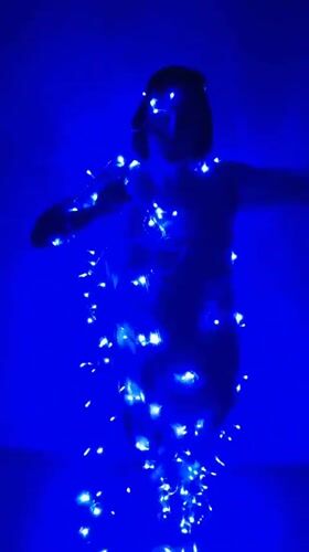 Woman dances with fairy lights in blue-lit room