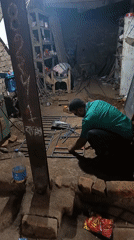 Welder works on metal grid in cluttered Bangladesh workshop