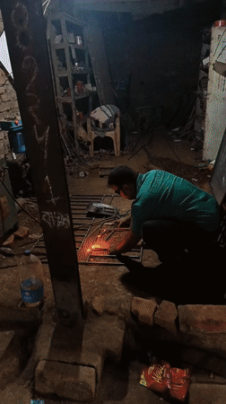 Welder works on metal grid in cluttered Bangladesh workshop