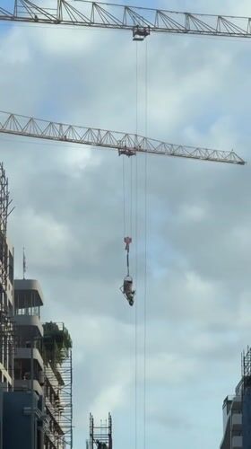 Yellow crane lifts cement bucket at Cape Town construction site