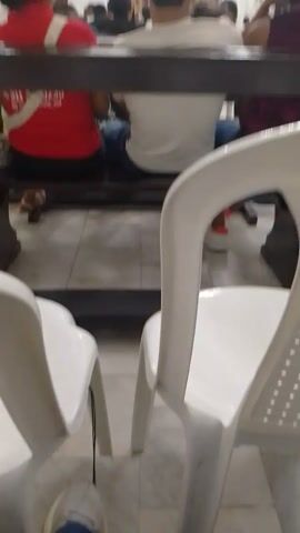 A video shot inside a church from behind, showing people sitting and praying. The focus is on the back of a head of a person in a white shirt in the middle. Behind the head is the altar with a statue of a saint and other religious iconography. The video shows the scene is in a church during a service.