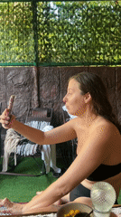 Woman checks phone in outdoor cabana setting