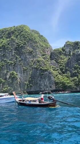 Longtail boat on turquoise bay, Ao Nang's cliffs behind