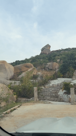 Car drives up hill road in Muddenahalli, India