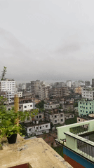 Rainy rooftop morning in Dhaka with a school worksheet in hand