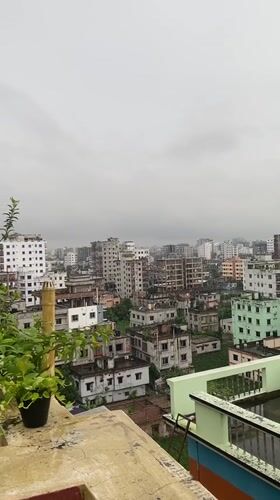 Rainy rooftop morning in Dhaka with a school worksheet in hand