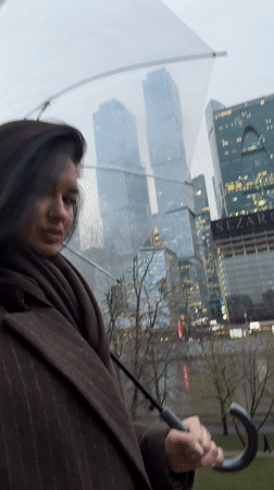 Woman with umbrella shelters from rain in urban setting
