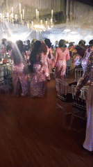 Women in pink dresses dance at wedding reception
