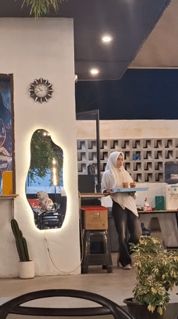 Street musician performs at busy Indonesian cafe during afternoon