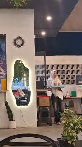 Street musician performs at busy Indonesian cafe during afternoon