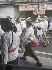 Traditional-dressed group walks through Denpasar street at night