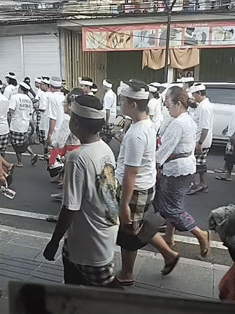 Traditional-dressed group walks through Denpasar street at night