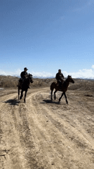 Two horsemen travel dirt path in rural Kyrgyzstan