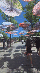 Colorful umbrella canopy lines a busy pedestrian walkway in Huairou