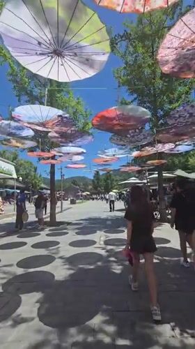 Colorful umbrella canopy lines a busy pedestrian walkway in Huairou