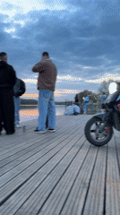 Scooter parked on pier as people gather in Veliky Novgorod