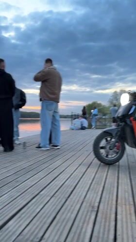 Scooter parked on pier as people gather in Veliky Novgorod