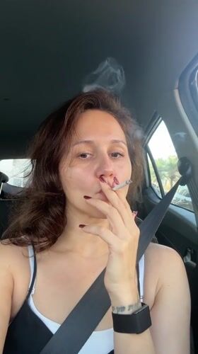 Woman smoking cigarette in car driver's seat in Dubai