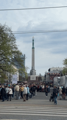 Crowd gathers around monument in Riga city square