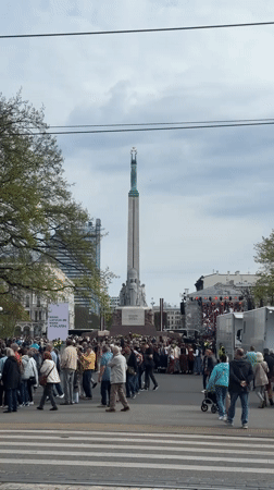 Crowd gathers around monument in Riga city square