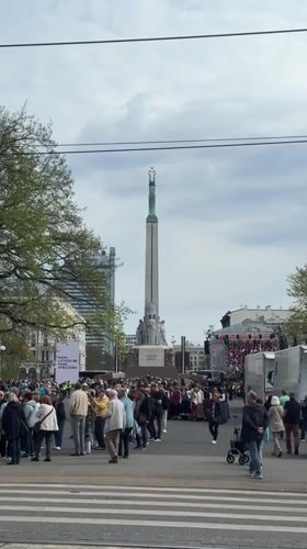 Crowd gathers around monument in Riga city square