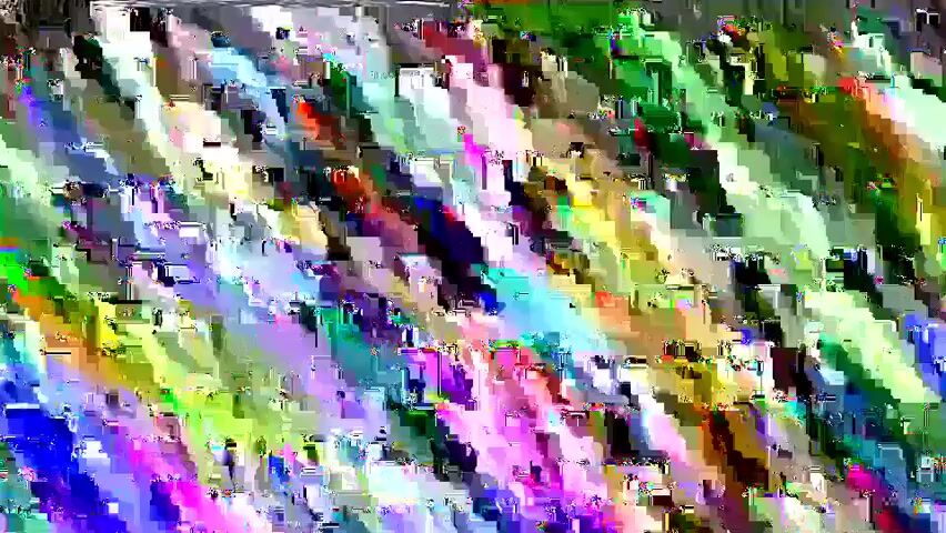 The video begins with a glitch effect, then shows a crow standing on a grassy area next to a paved path. The crow is facing to the left and appears to be pecking at something on the ground. The ground is covered in dry leaves and grass. There is a tree trunk on the left side of the frame. The lighting suggests it is daytime.