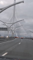 First-person highway drive beneath a modern cable-stayed bridge