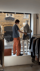 Man adjusts mannequins in London store window display