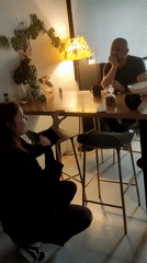 Woman laughs while crouched near kitchen table in Saint Petersburg