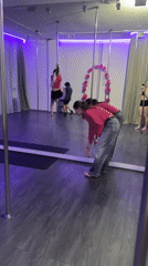 Pole dancing practice session documented at purple-lit studio
