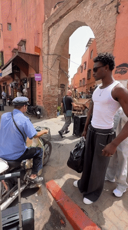 Busy morning in Marrakesh's medina, luggage, locals, and a sleeping cat