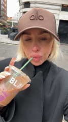 Woman drinks iced coffee on London street Friday morning