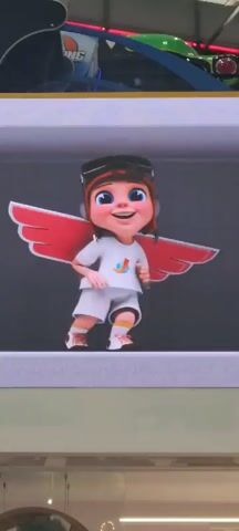 Here is a description of the video:
The video shows a smiling cartoon girl wearing a white shirt and shorts, goggles, and headphones. Red wings are behind the girl. She is in front of a gray background. A portion of a ride is visible in the background above her. The camera slightly zooms in on the girl.