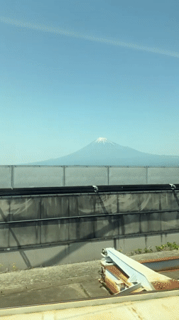 Train passenger films Mount Fuji through window on clear day