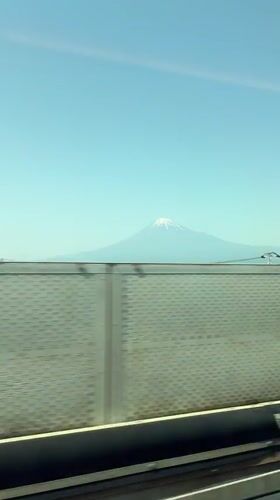 Train passenger films Mount Fuji through window on clear day