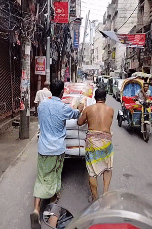 Workers push loaded handcart through narrow Dhaka street
