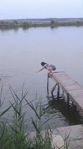 Jumping off a wooden pier into a calm Moldova lake