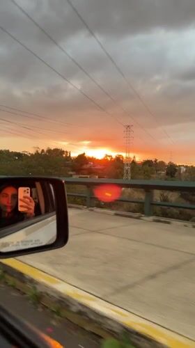 Vehicle crosses bridge during orange sunset in Mexico City