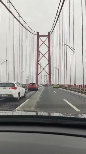 Driver crosses red-towered suspension bridge in Lisbon