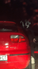 Masked person at roadside with pulled-over red car