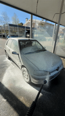 Car owner washes silver Peugeot at self-service facility