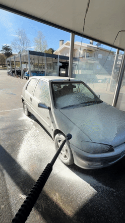 Car owner washes silver Peugeot at self-service facility
