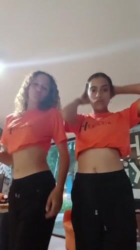 Two women dance in matching outfits in Playa El Agua