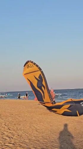 Kitesurfing session on a Denpasar beach with outrigger boats nearby